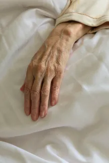 persons left hand on white textile by Bruce Tang courtesy of Unsplash.