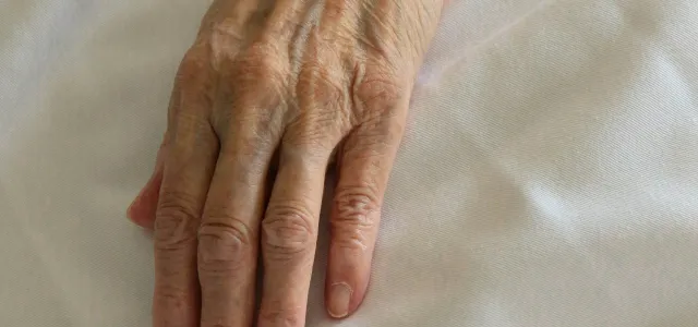 persons left hand on white textile by Bruce Tang courtesy of Unsplash.